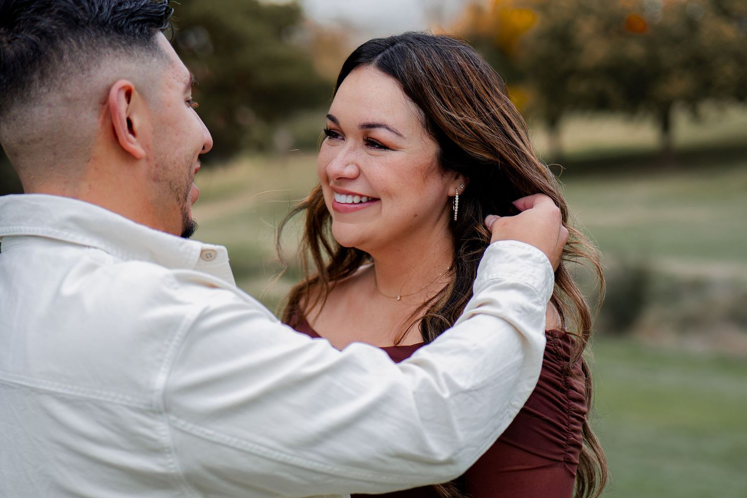 Romantic couple sharing tender moments together in a sunlit outdoor setting during a photo session.