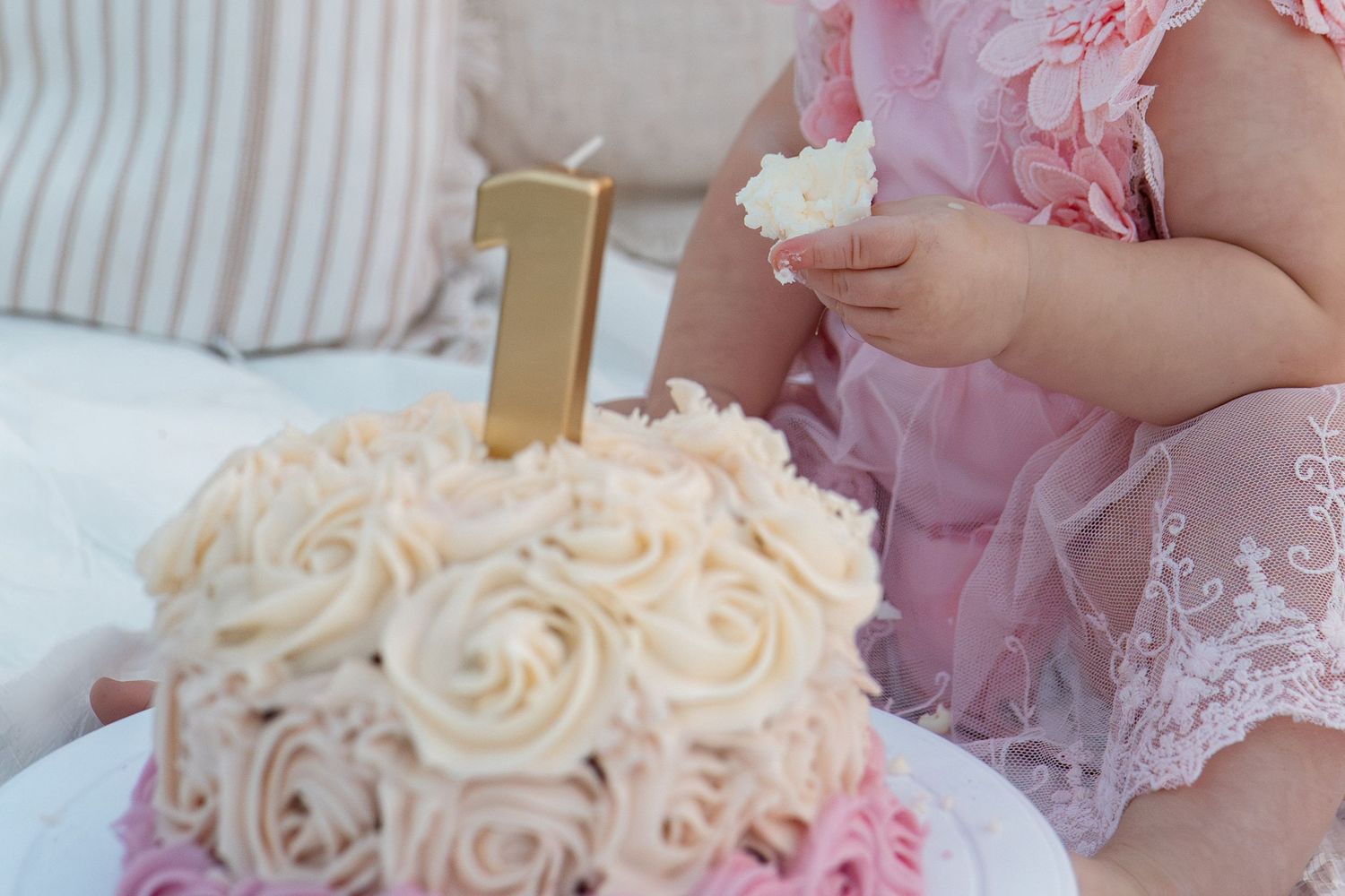 Pink and white frosted cake decorated with roses and gold accents in Roseville, CA