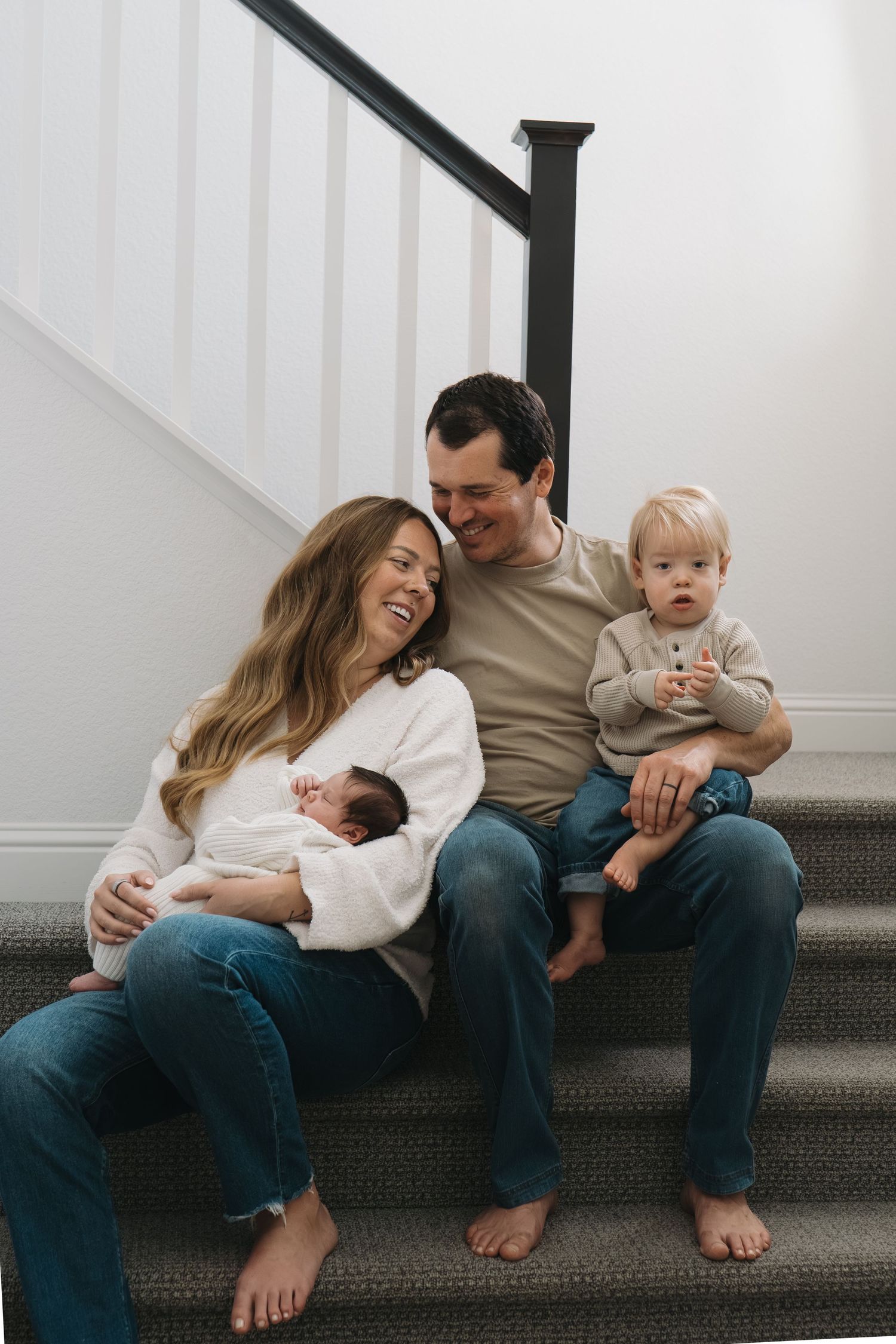 Family sitting together on carpeted stairs in a bright white room in Roseville, CA