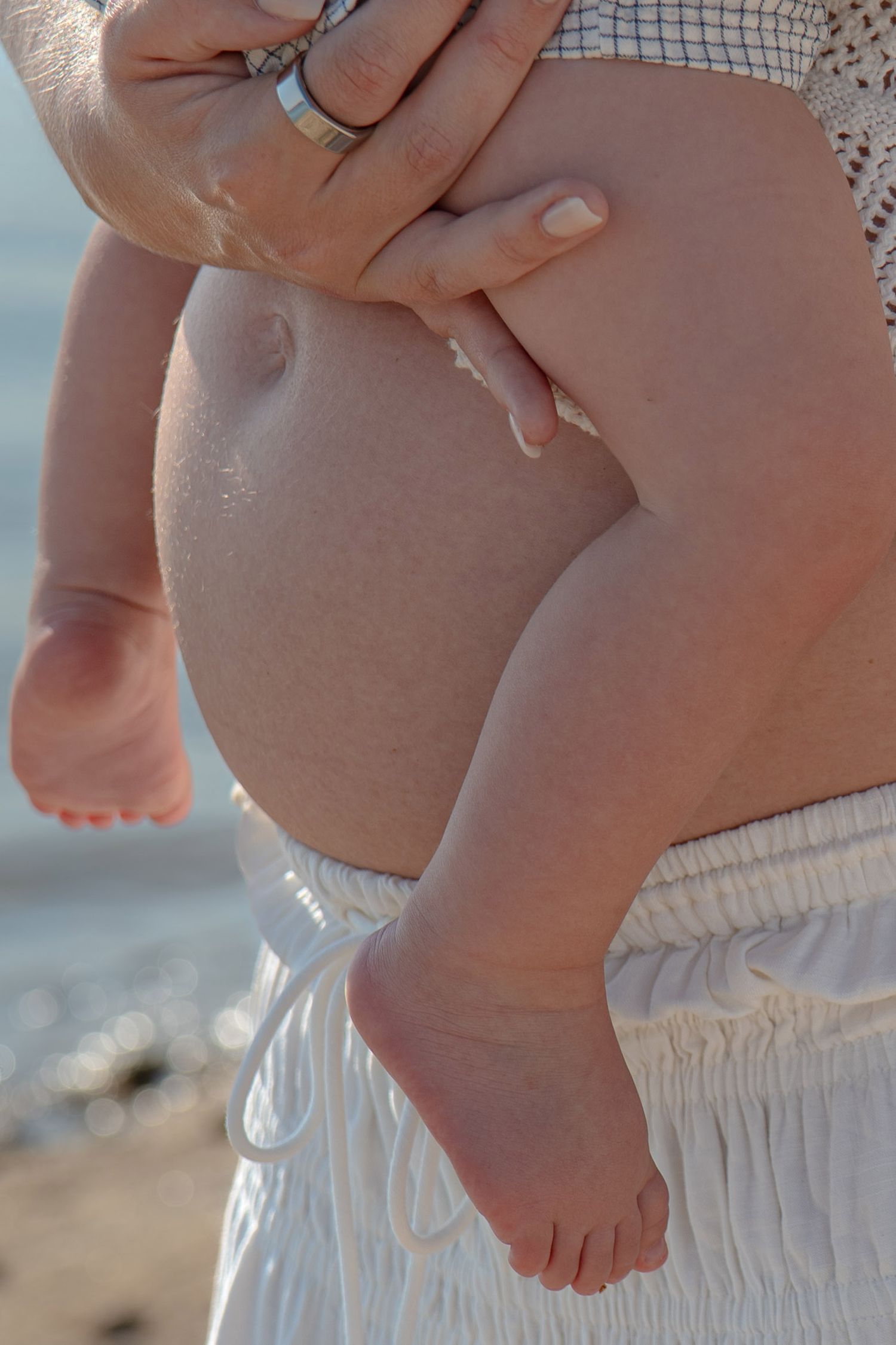 Close-up of baby's feet being held against beach backdrop in Roseville, CA