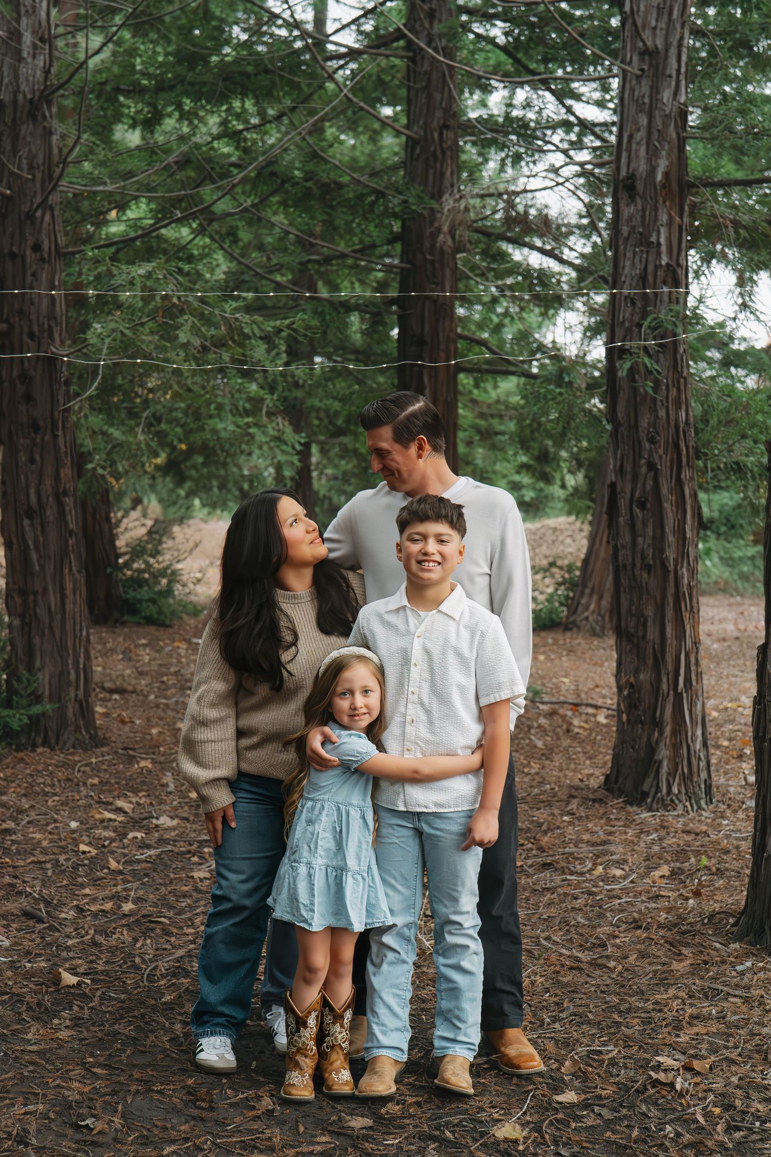 Family portrait session among tall redwood trees with everyone wearing casual coordinated outfits in Roseville, CA