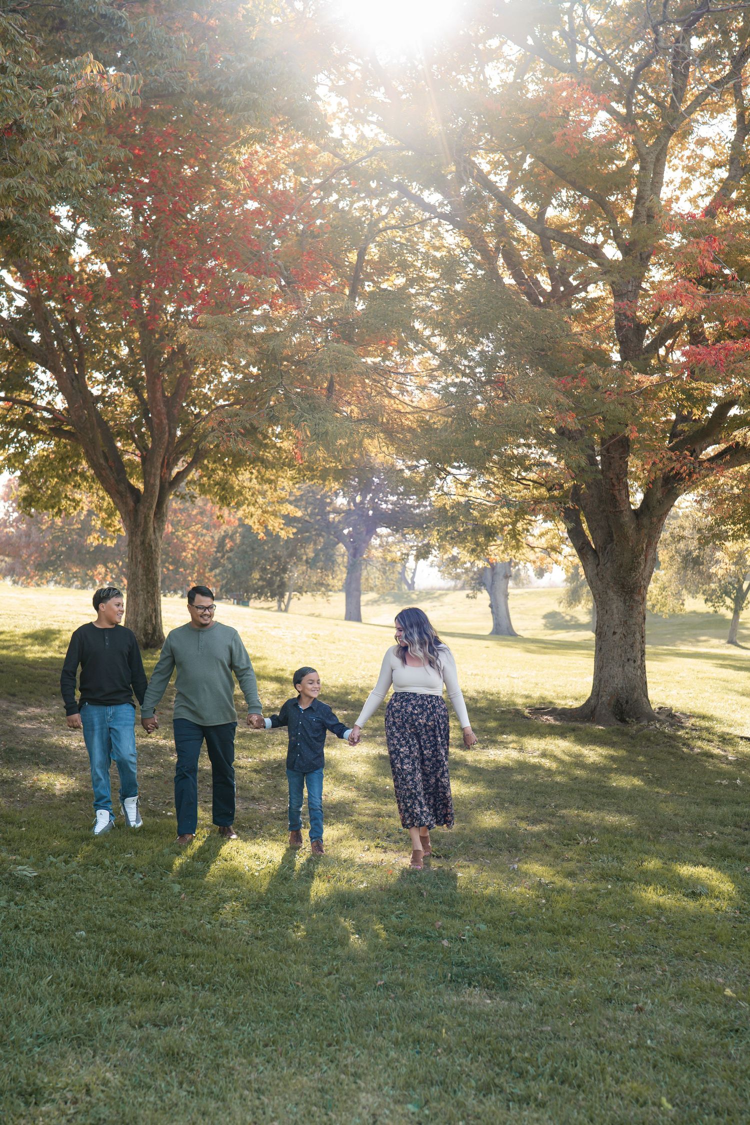 Family walking together under golden sunlit trees during fall season in Roseville, CA