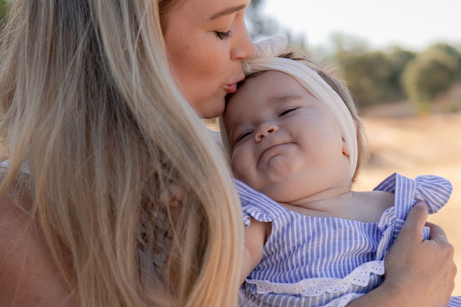 Tender outdoor portrait series of parent and baby in soft sunlight.