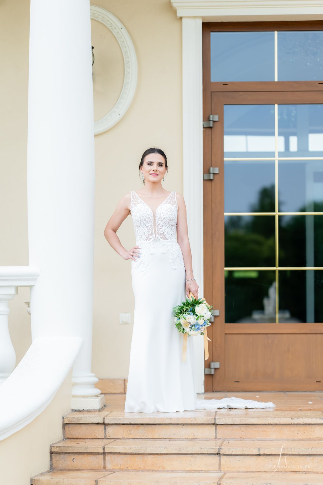 Panna Młoda w eleganckiej sukni ślubnej pozująca na tle budynku Domu Weselnego Janowice