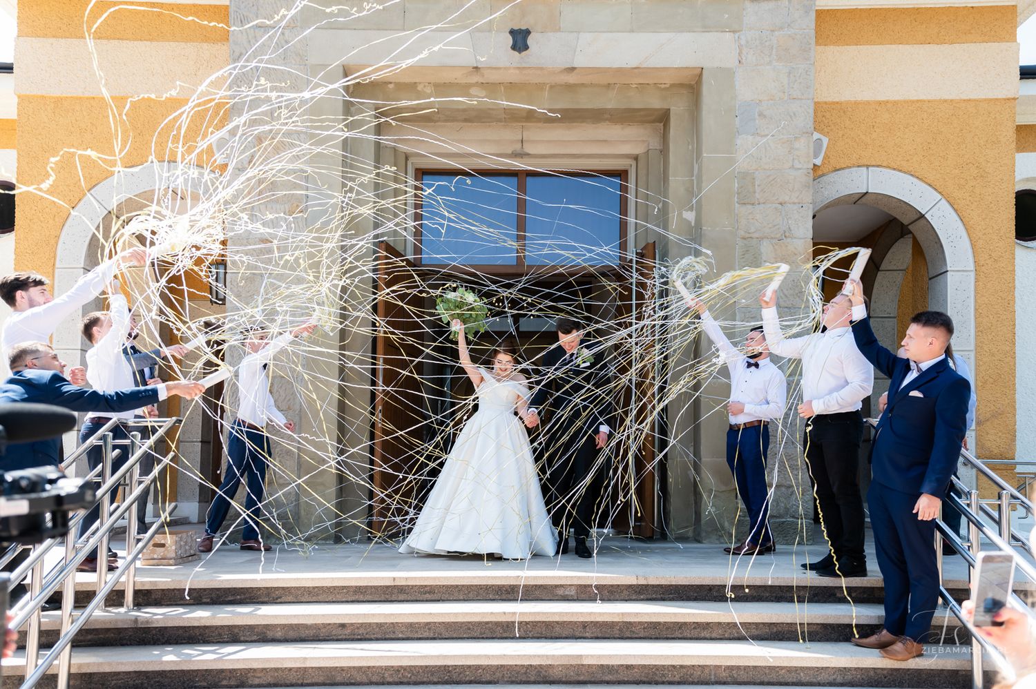 Efektowne wyjście pary młodej z kościoła, motyw ze wstążkami, fotograf ślubny Straszęcin
