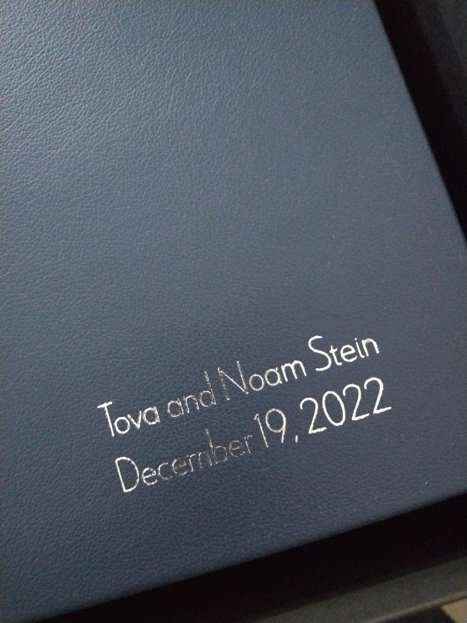 Close-up view of handwritten text in white ink on a dark blue photo ablum showing date and names.