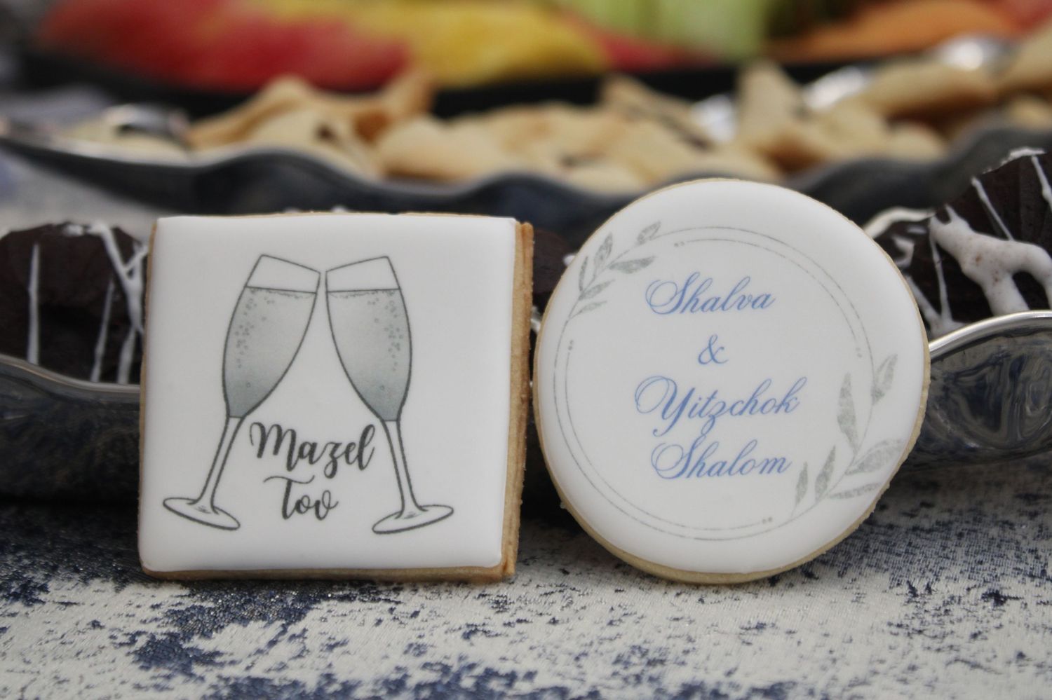 Wedding-themed decorative cookie showing champagne glasses and personalized text on white circular and square surfaces.