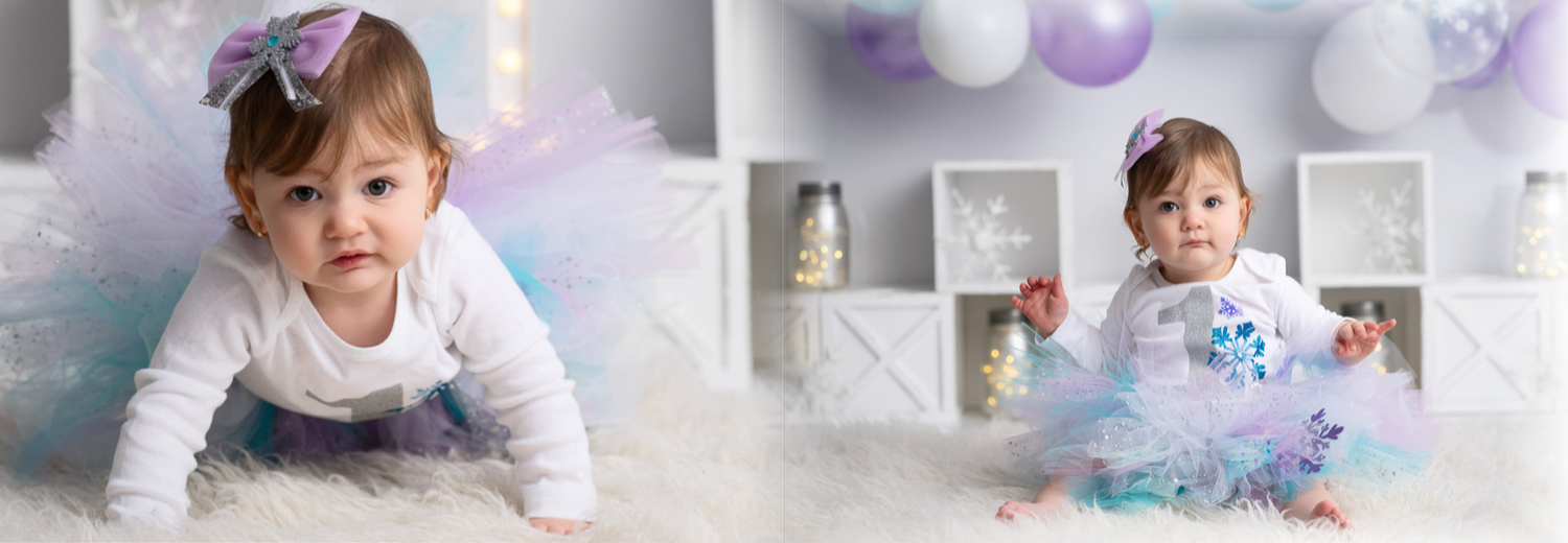 A baby in pastel blue and purple outfits crawls and plays with balloons during a first birthday photo session.