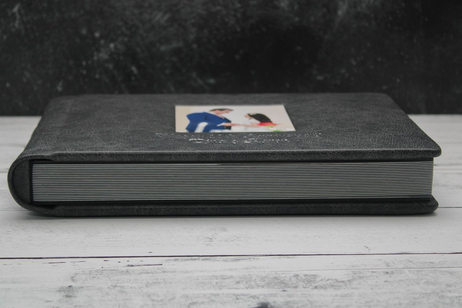 Side view of anniversary photo album in gray distressed leather with elegant cameo window design