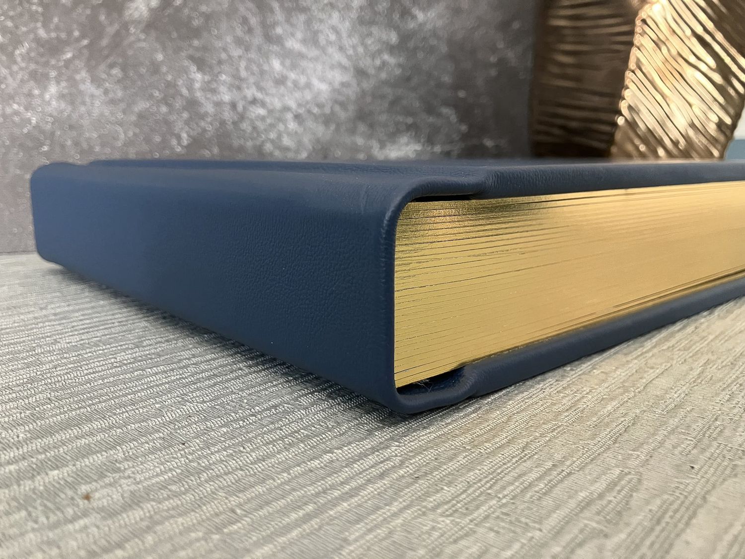 Cobalt blue leather photo album cover with elegant gold page gilding, showcasing timeless craftsmanship.