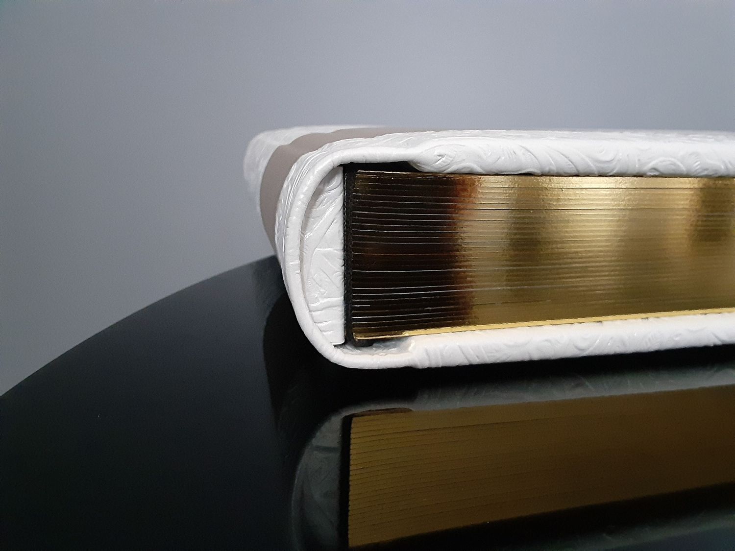 Genuine white leather photo album with gold page gilding displayed elegantly on a baby grand black piano