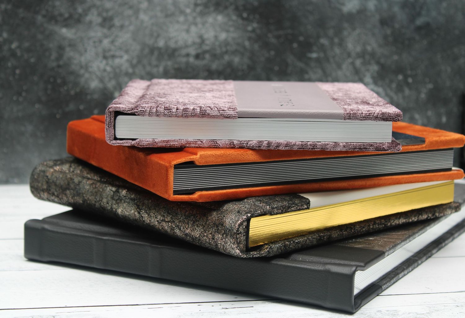 Colorful photo albums arranged in a stack on a white surface with a dark marbled background