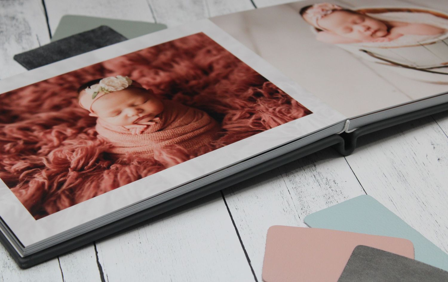 Baby album displayed on white wooden surface with colors watches in the background