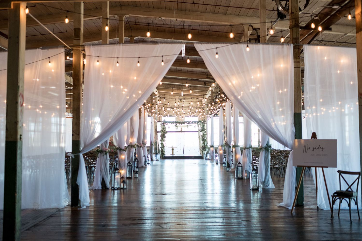 Tent-style indoor wedding reception with strung lights creating a warm, romantic atmosphere.
