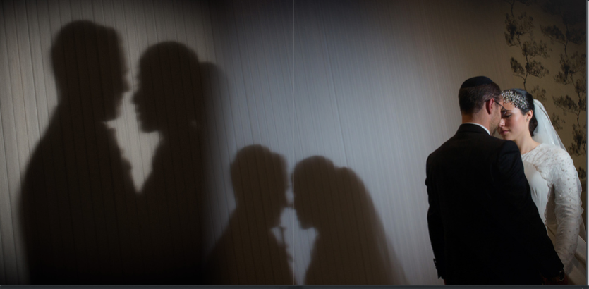 Silhouettes of people dancing and celebrating at a dimly lit wedding.
