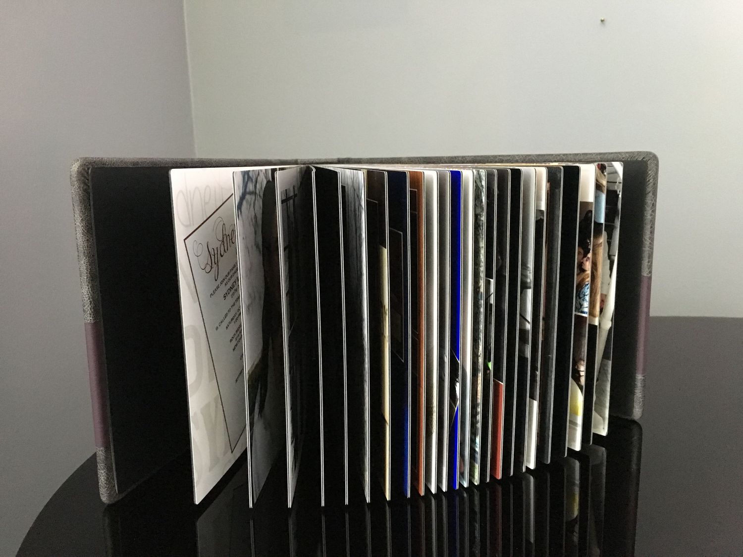 Fanned out photo album displayed on a black surface, showcasing its pages and elegant design.