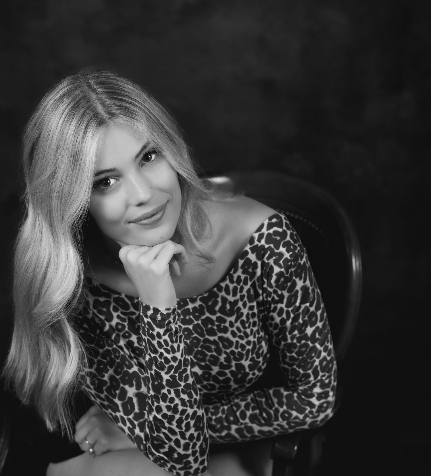 Studio portrait featuring leopard print top against dark background.