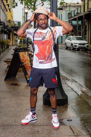 Street style photo showing casual sportswear and sneakers on a rainy city sidewalk.