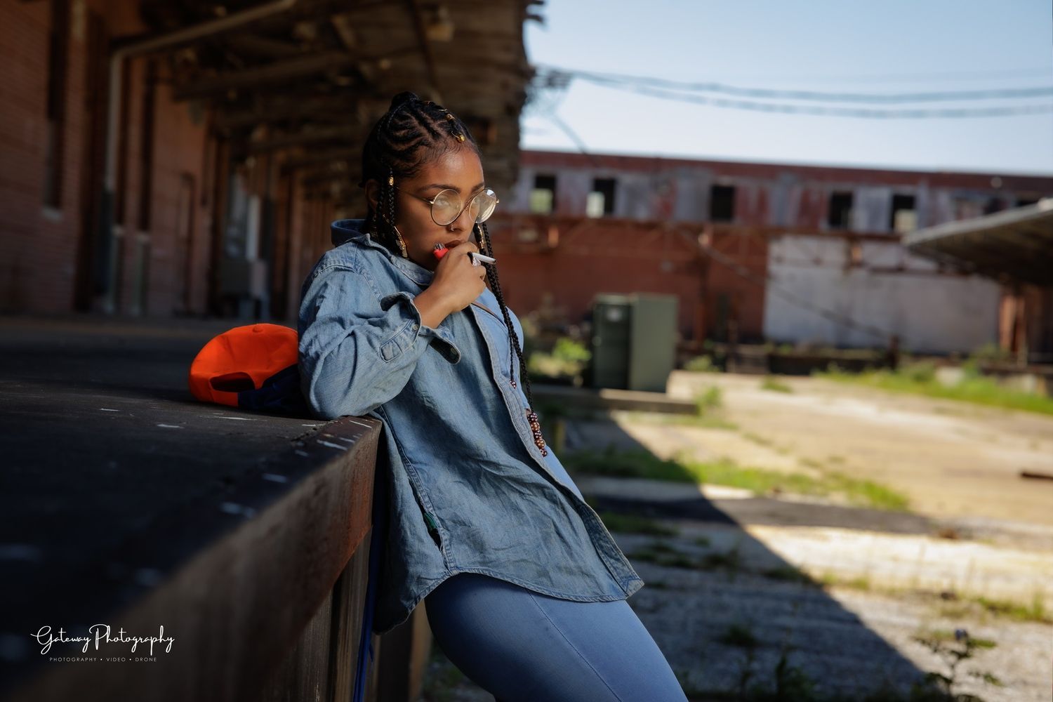 Artistic portrait of someone in denim jacket against urban industrial background.