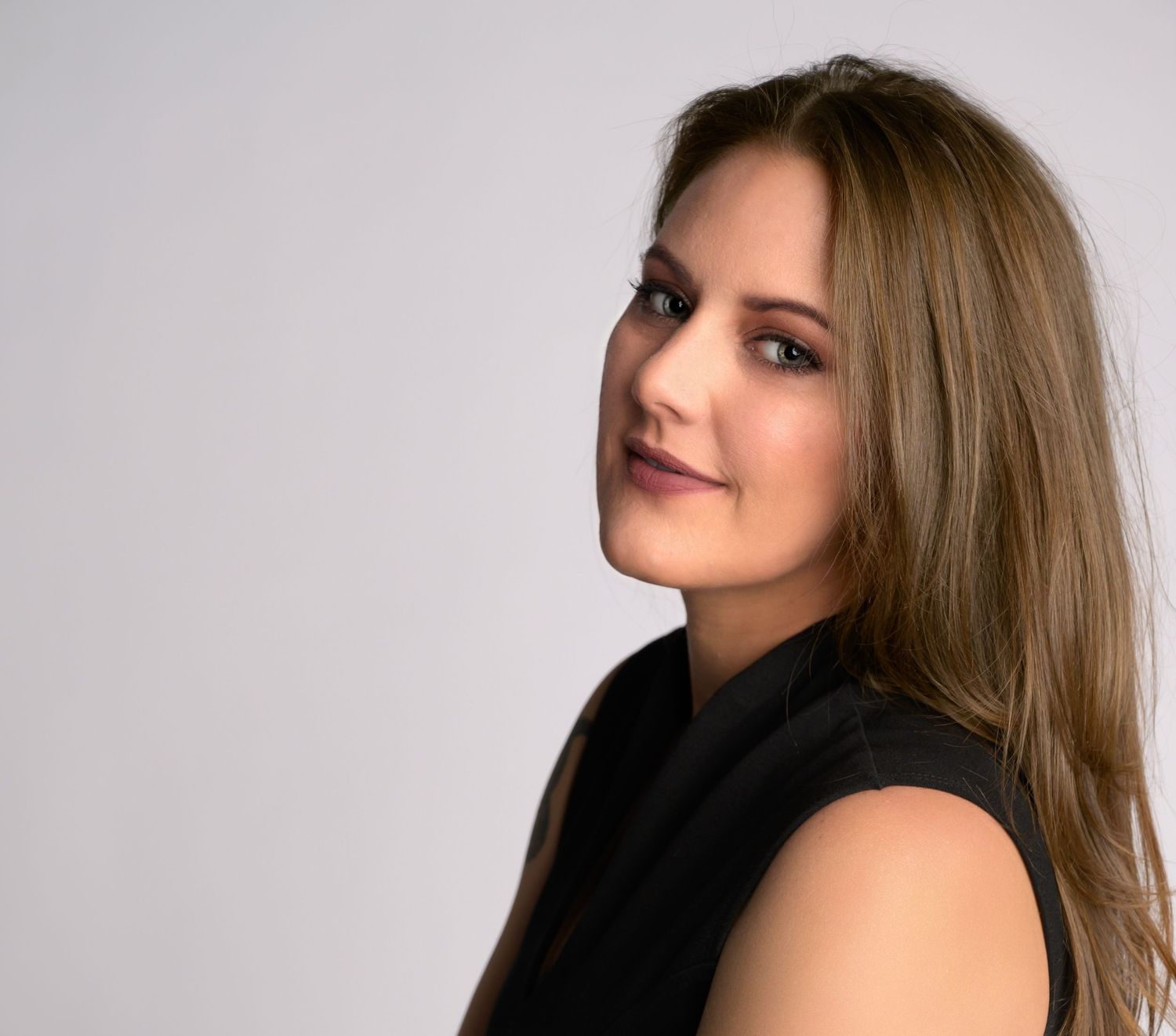 Professional headshot against light gray background featuring sleek black attire.