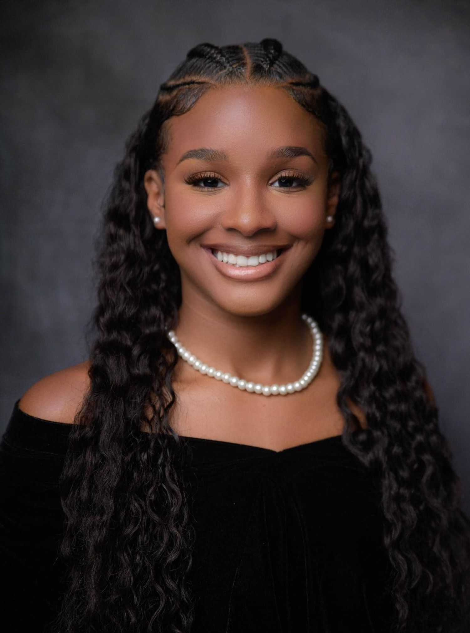 Photograhy, photographer, Elegant portrait featuring pearl necklace, black off-shoulder dress, and curly hairstyle against dark background.