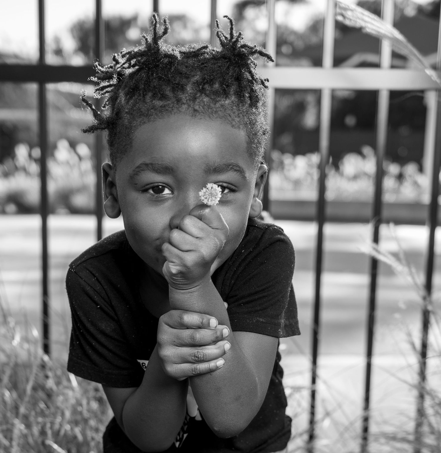 A black and white portrait of a child with curly hair covering their face while laughing playfully.