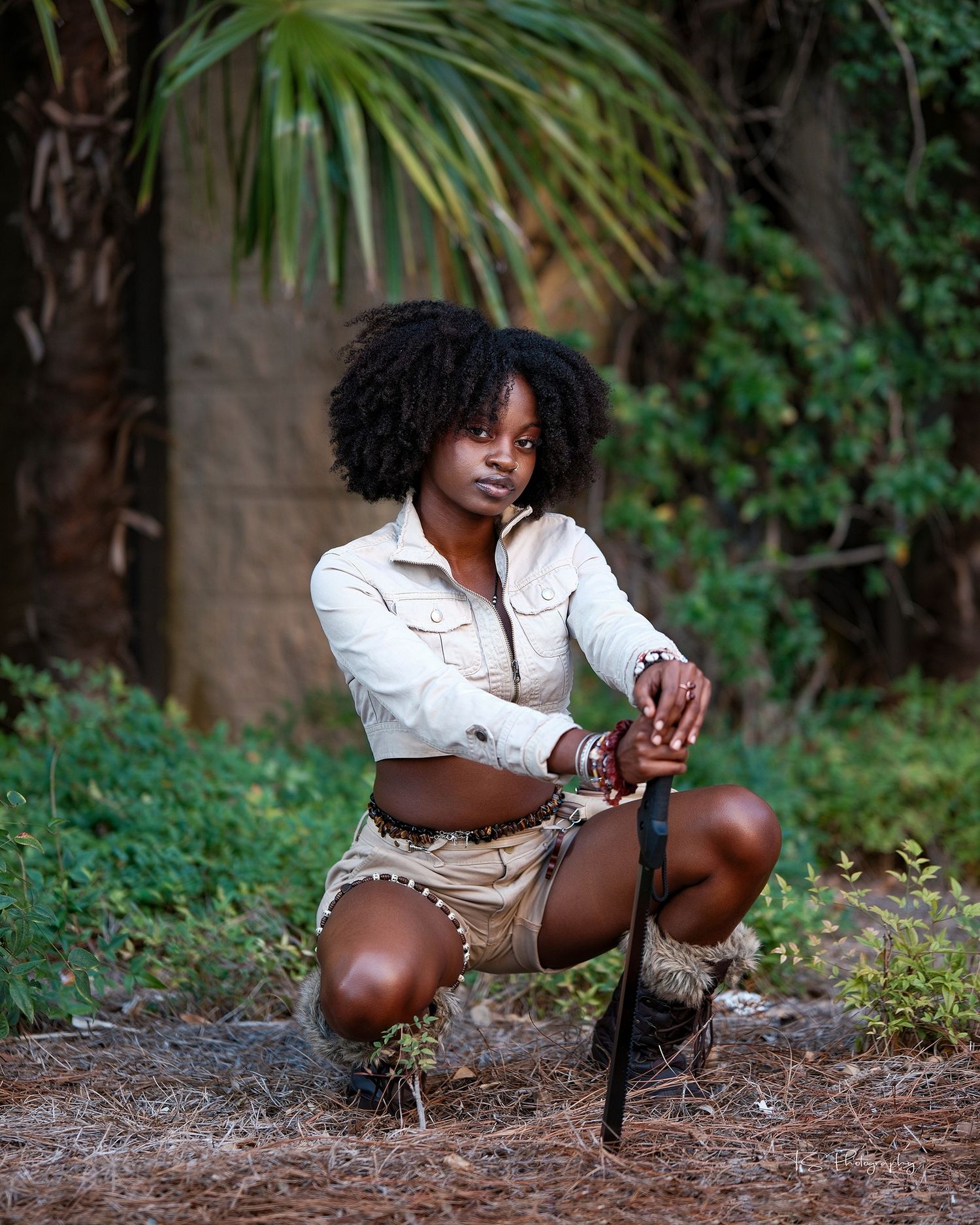 Outdoor portrait of person in white shirt and shorts crouching in tropical setting.