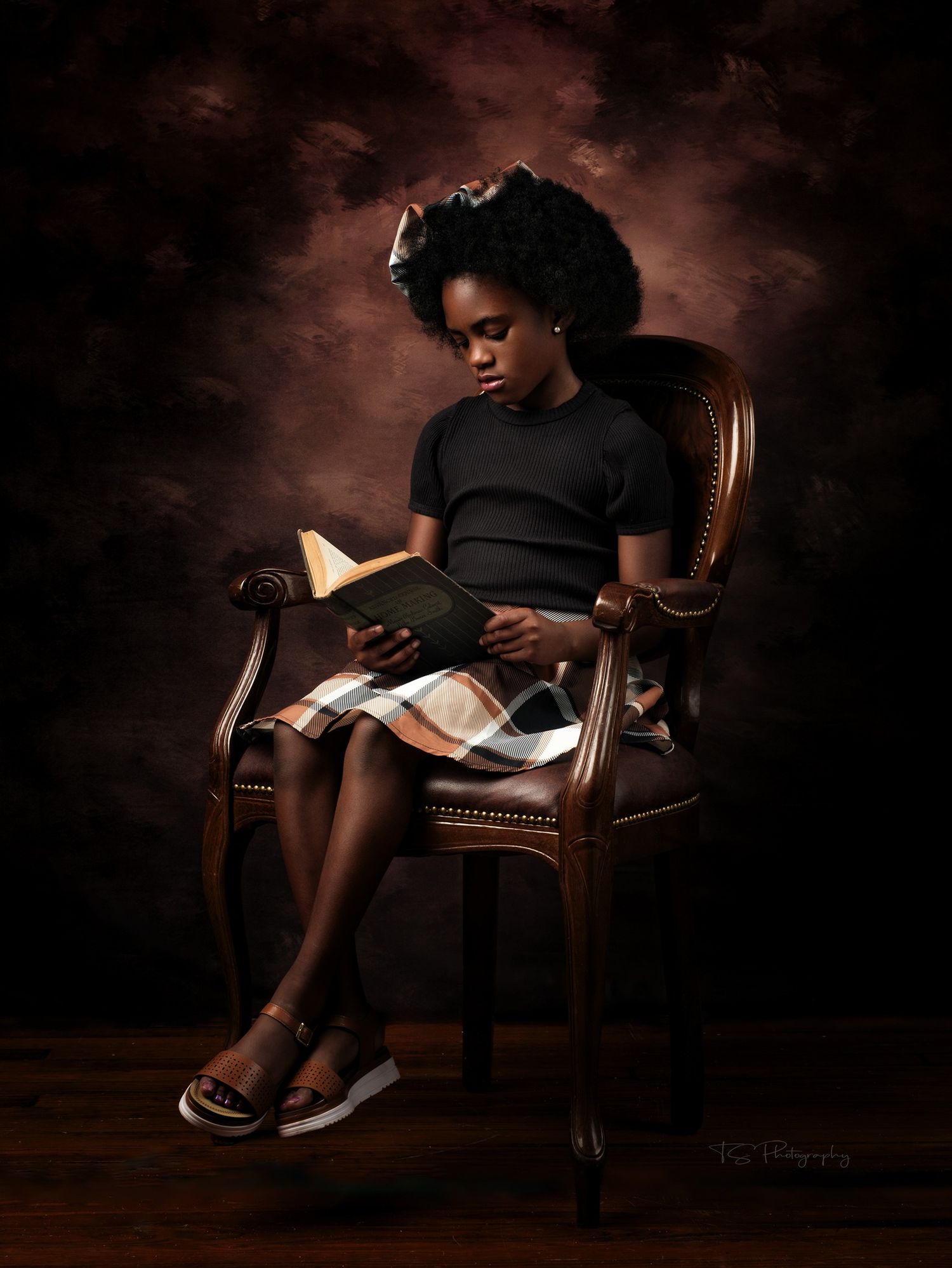 A quiet reading moment captured in moody lighting as a person sits in an antique wooden chair with a book.