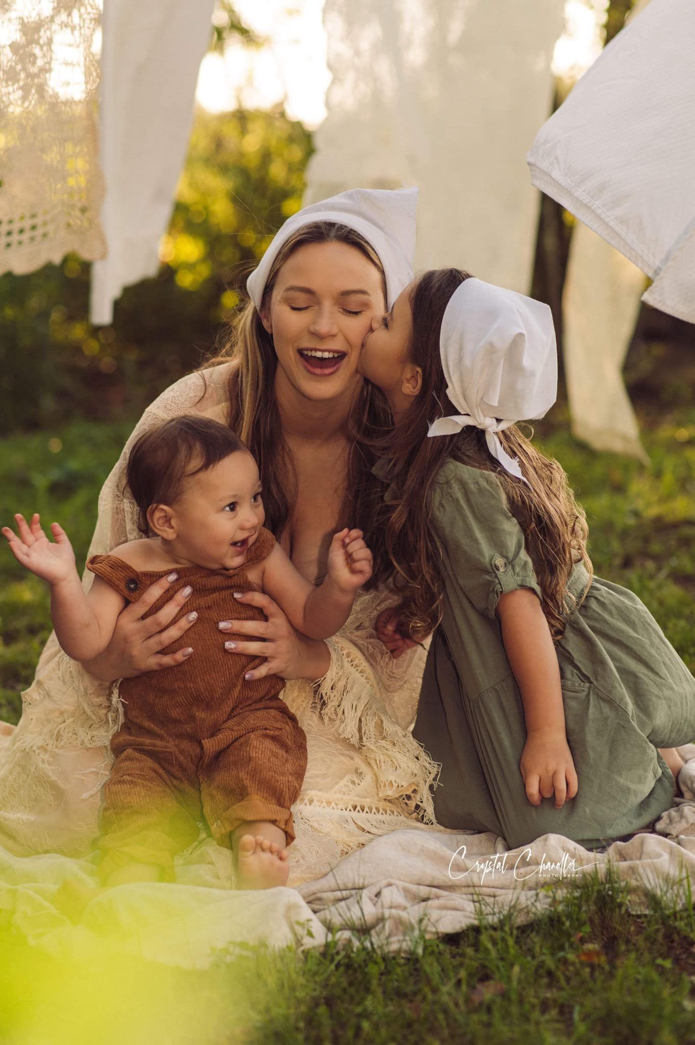 Photograhy, photographer, Mobile, AL A joyful family moment captured outdoors with white linens and sunlit background in vintage style.