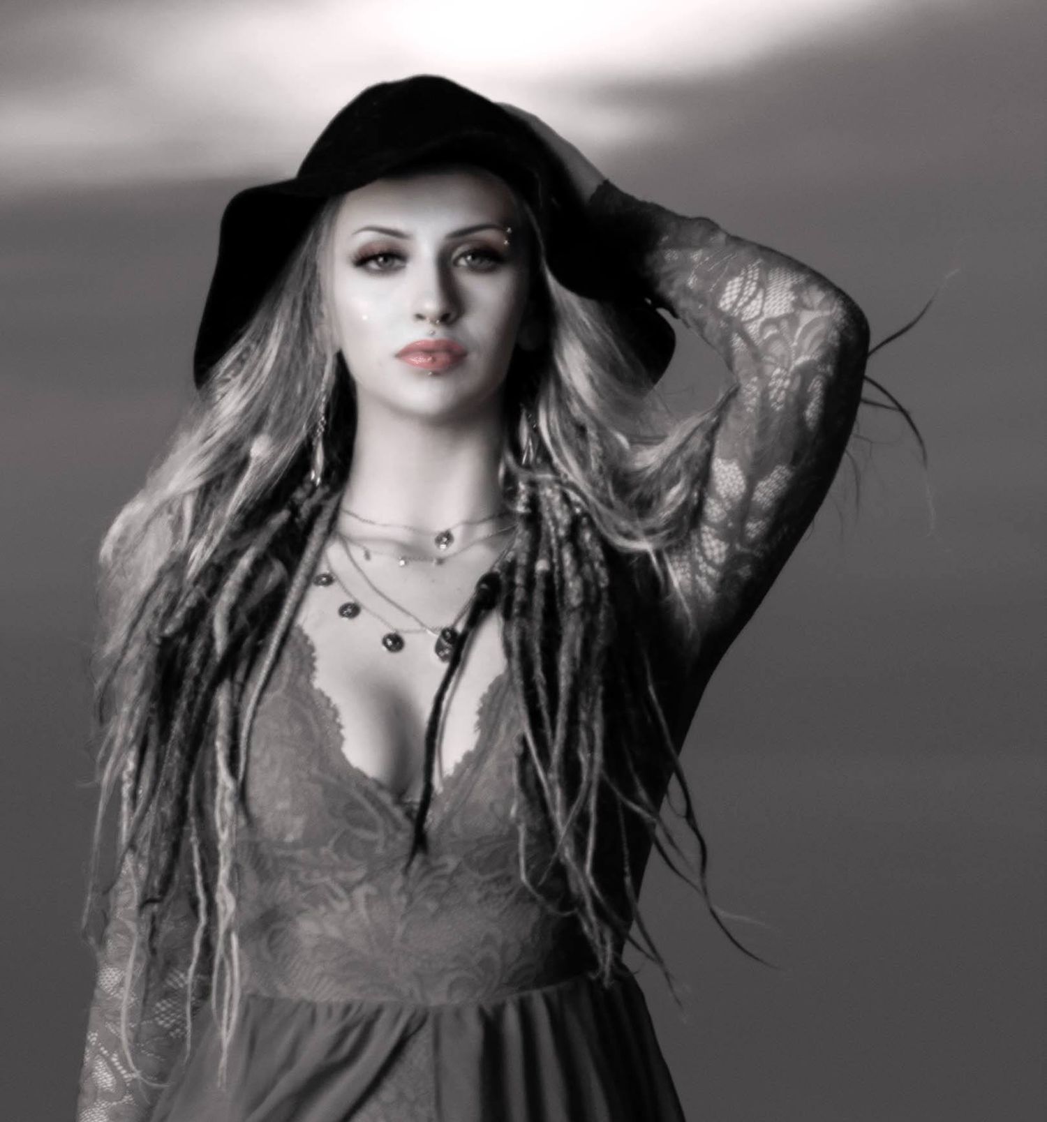 Dramatic black and white portrait with wide-brimmed hat and flowing dress.