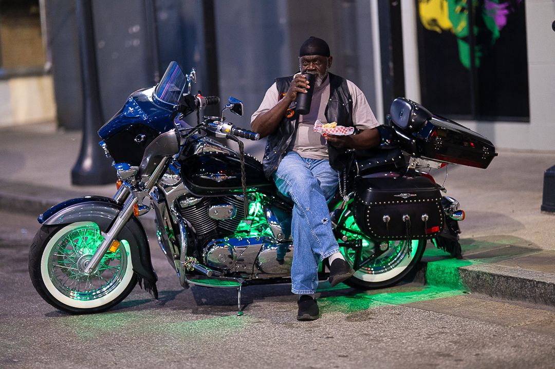 Motorcyclist sitting on custom bike with green underglow lights at night.