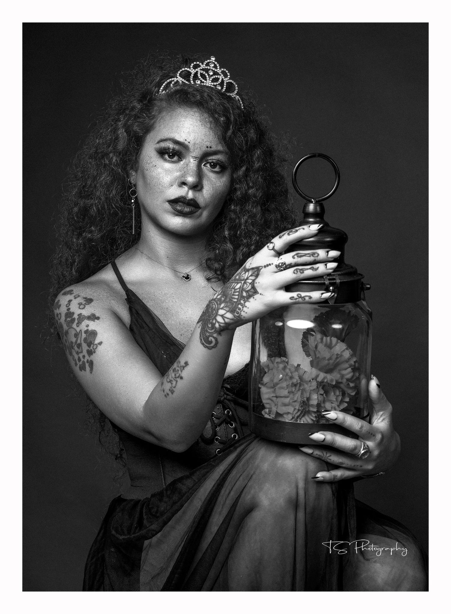 Dramatic black and white portrait with a decorative glass jar and tiara in a vintage glamour style.