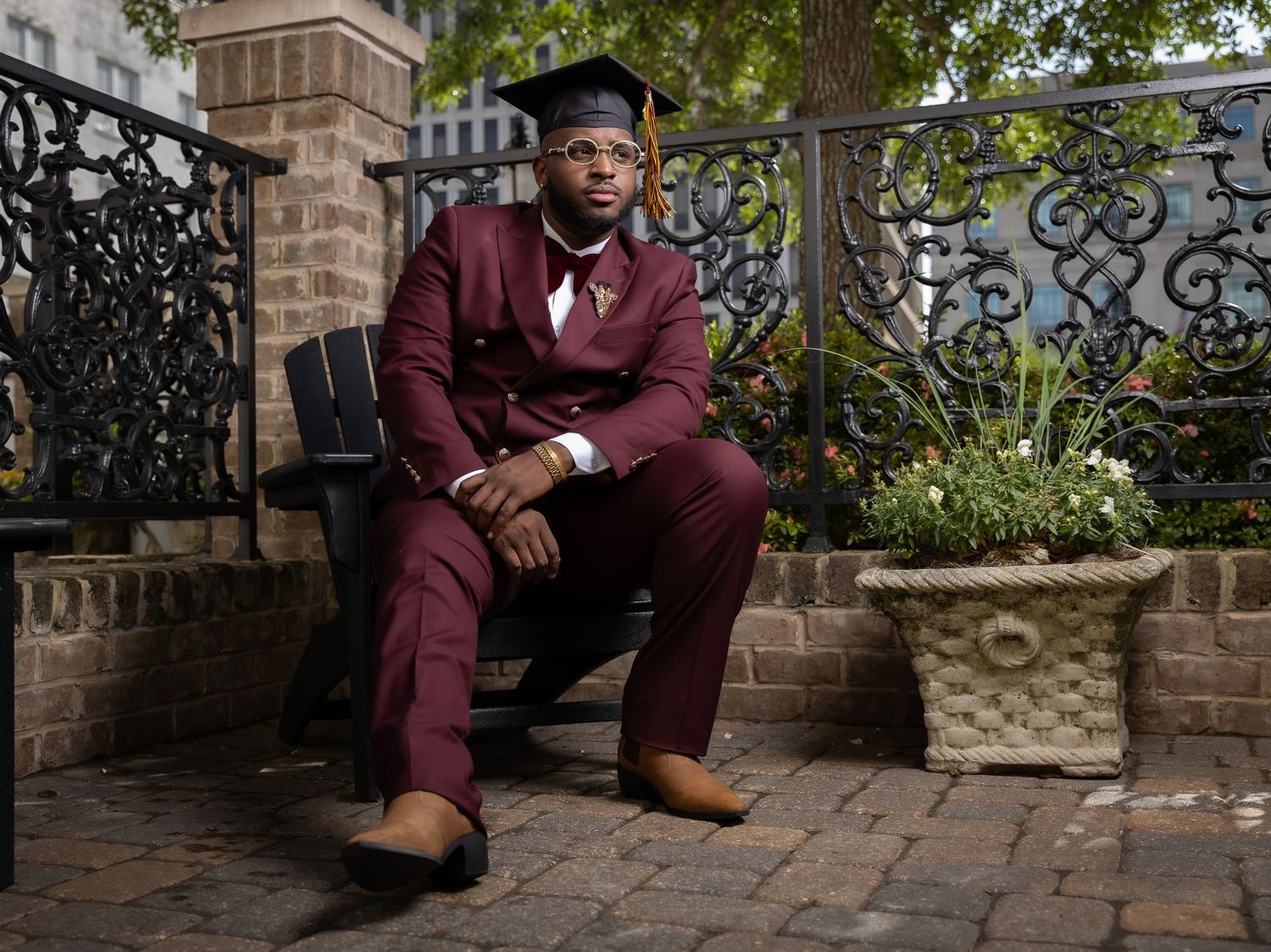 Professional portrait in burgundy suit seated on outdoor stone steps.
