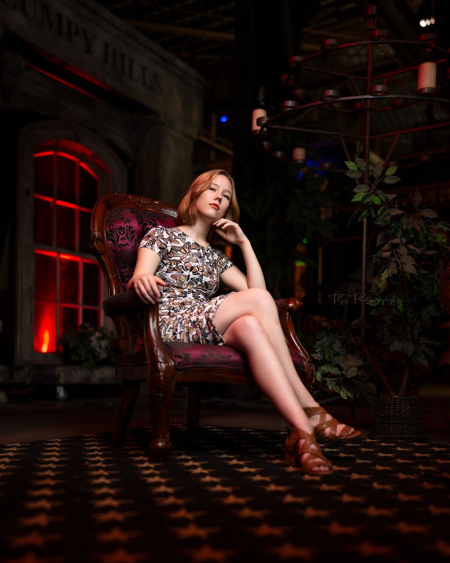 Dramatic portrait in floral dress at moody venue with red lighting and checkered floor.