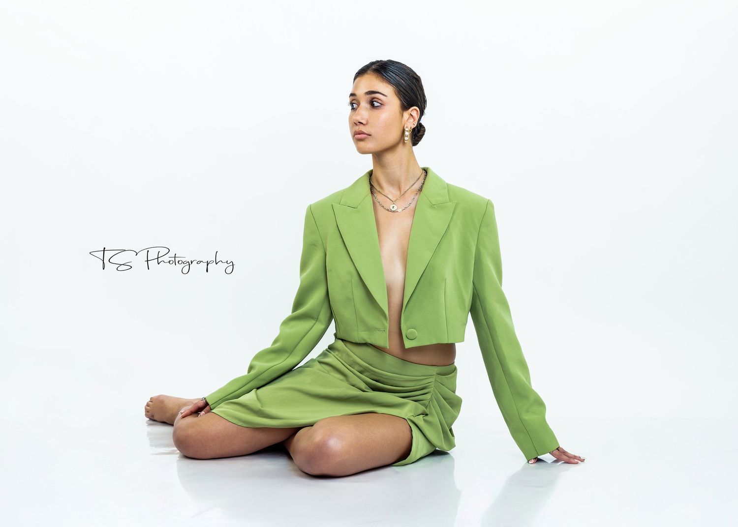 Professional fashion photo of a model in a stylish lime green blazer and shorts set against a white backdrop.