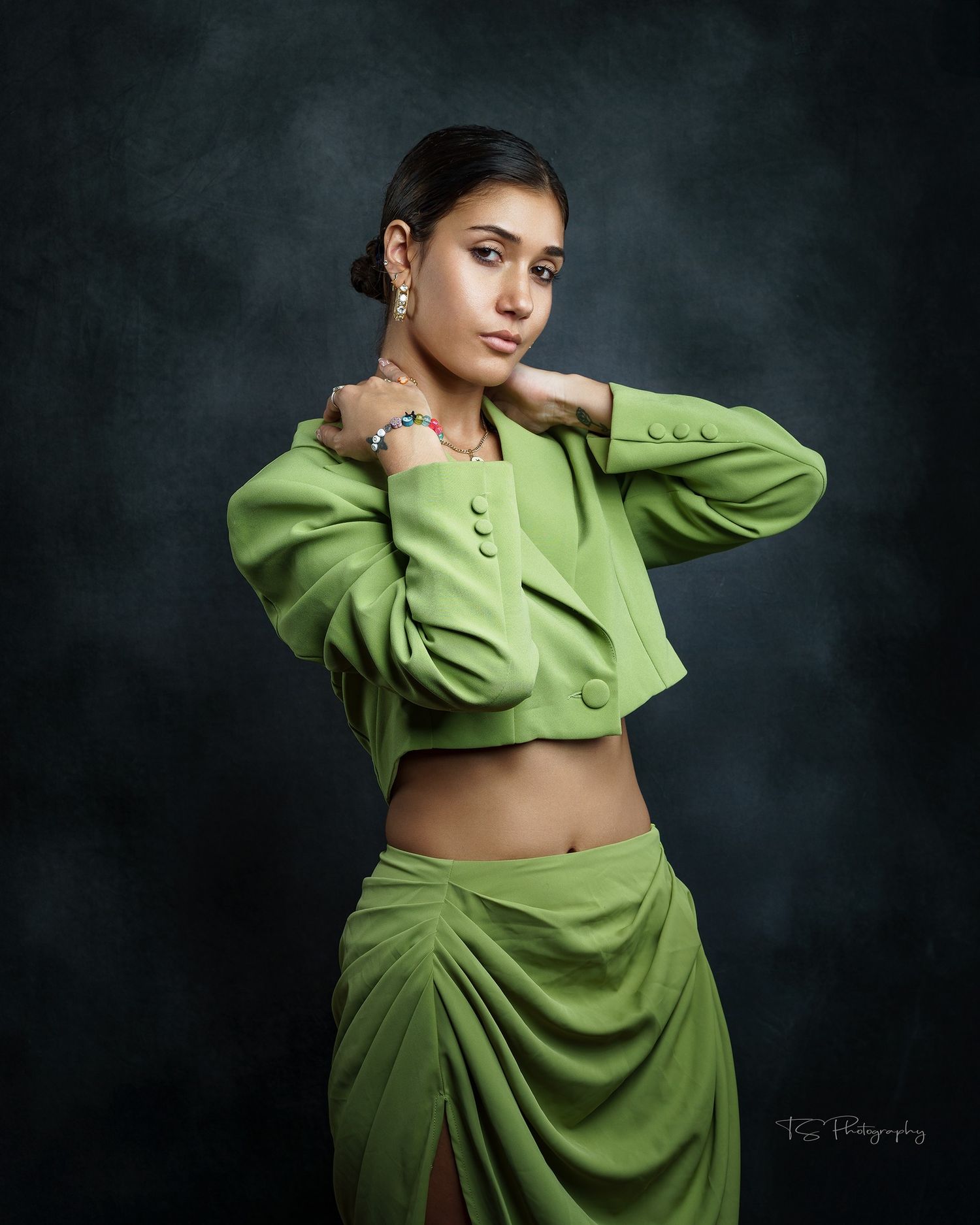 Fashion portrait featuring a cropped lime green jacket and draped skirt against a dark background.