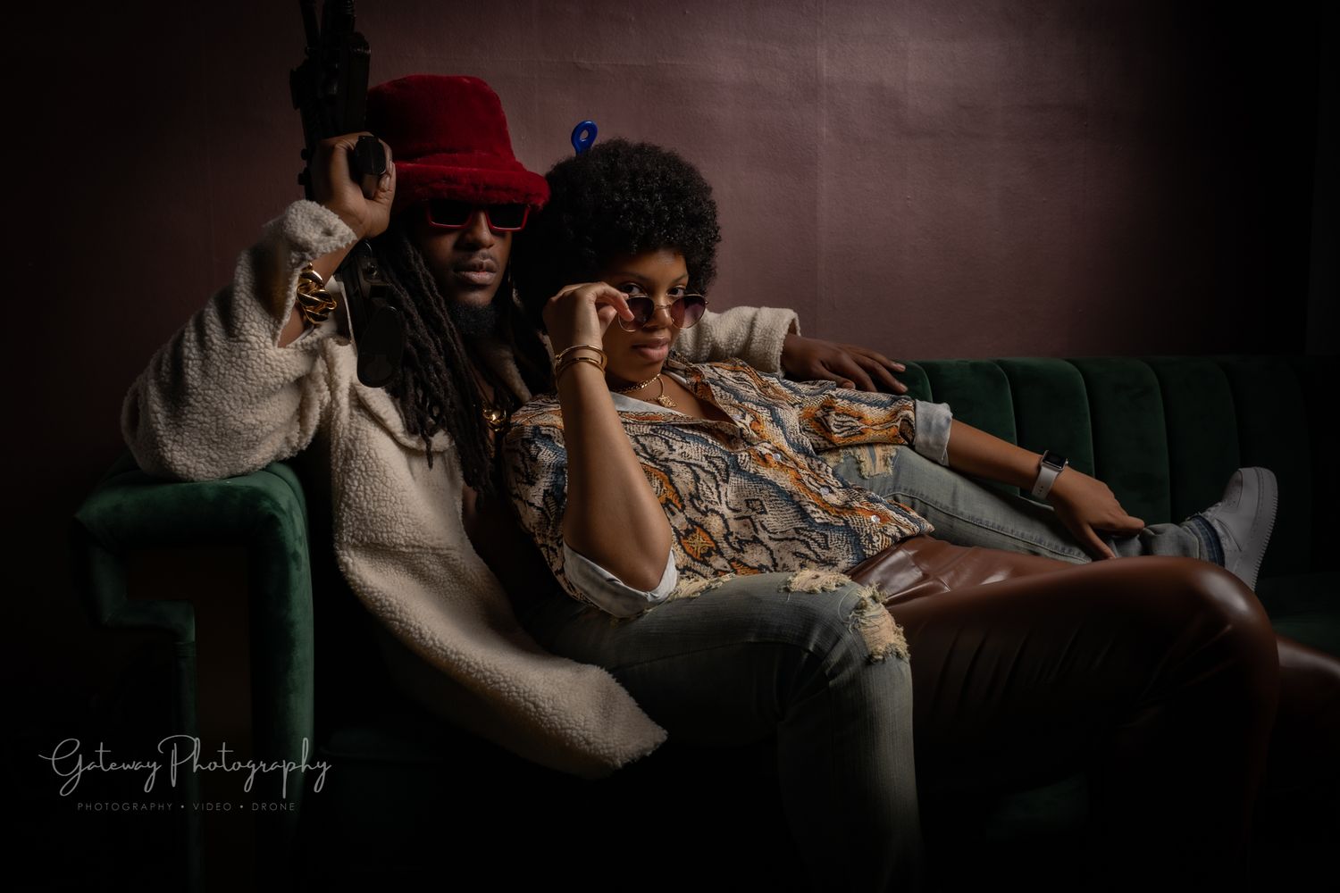 Two people relaxing on green couch in dim atmospheric lighting.