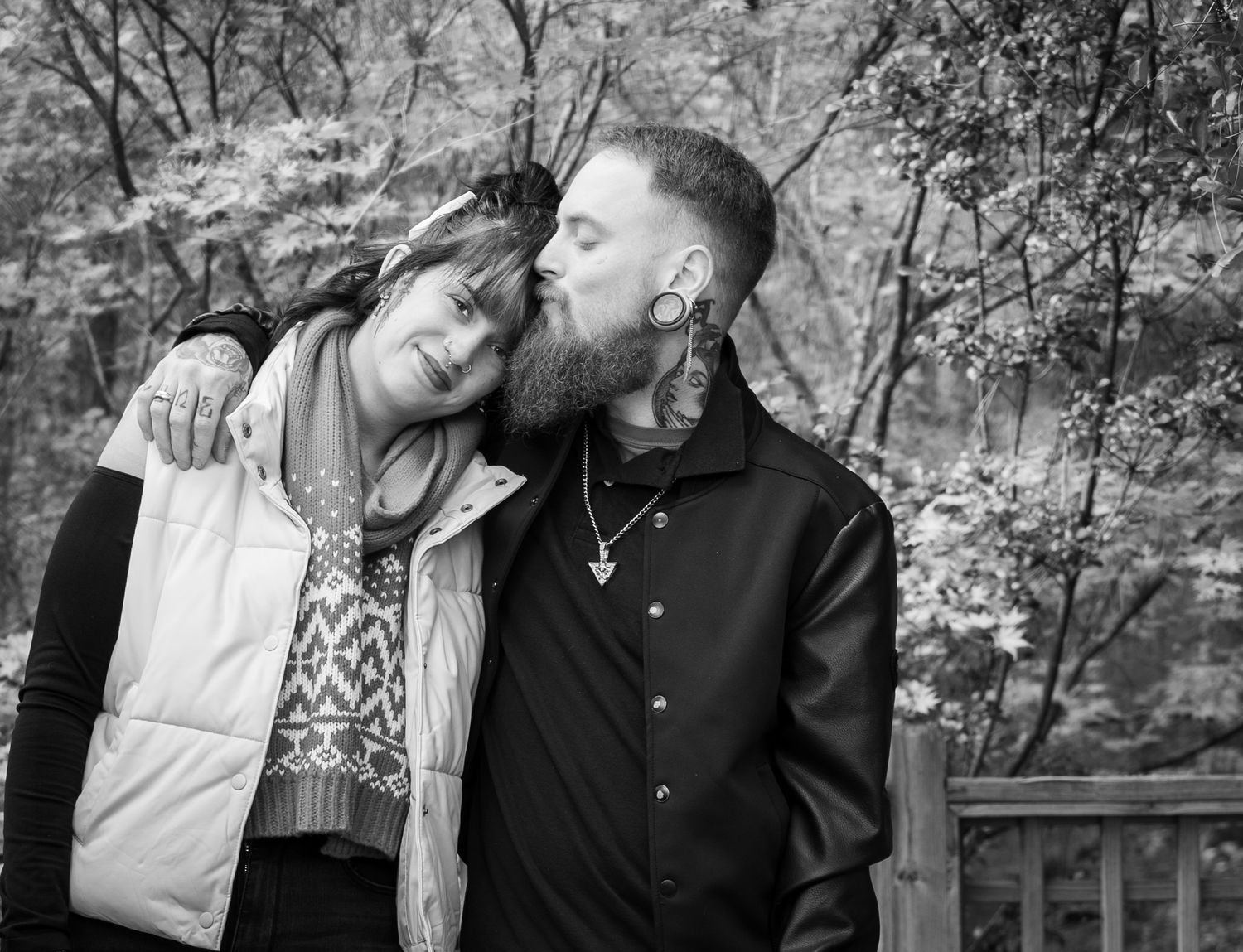 Black and white portrait of couple sharing intimate moment outdoors.
