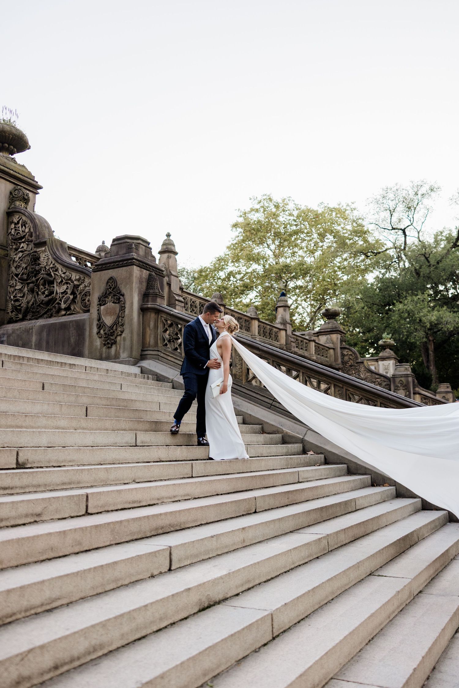 NYC elopement on Central Park steps — newlyweds embracing on stone staircase surrounded by lush park greenery. Manhattan New York City.