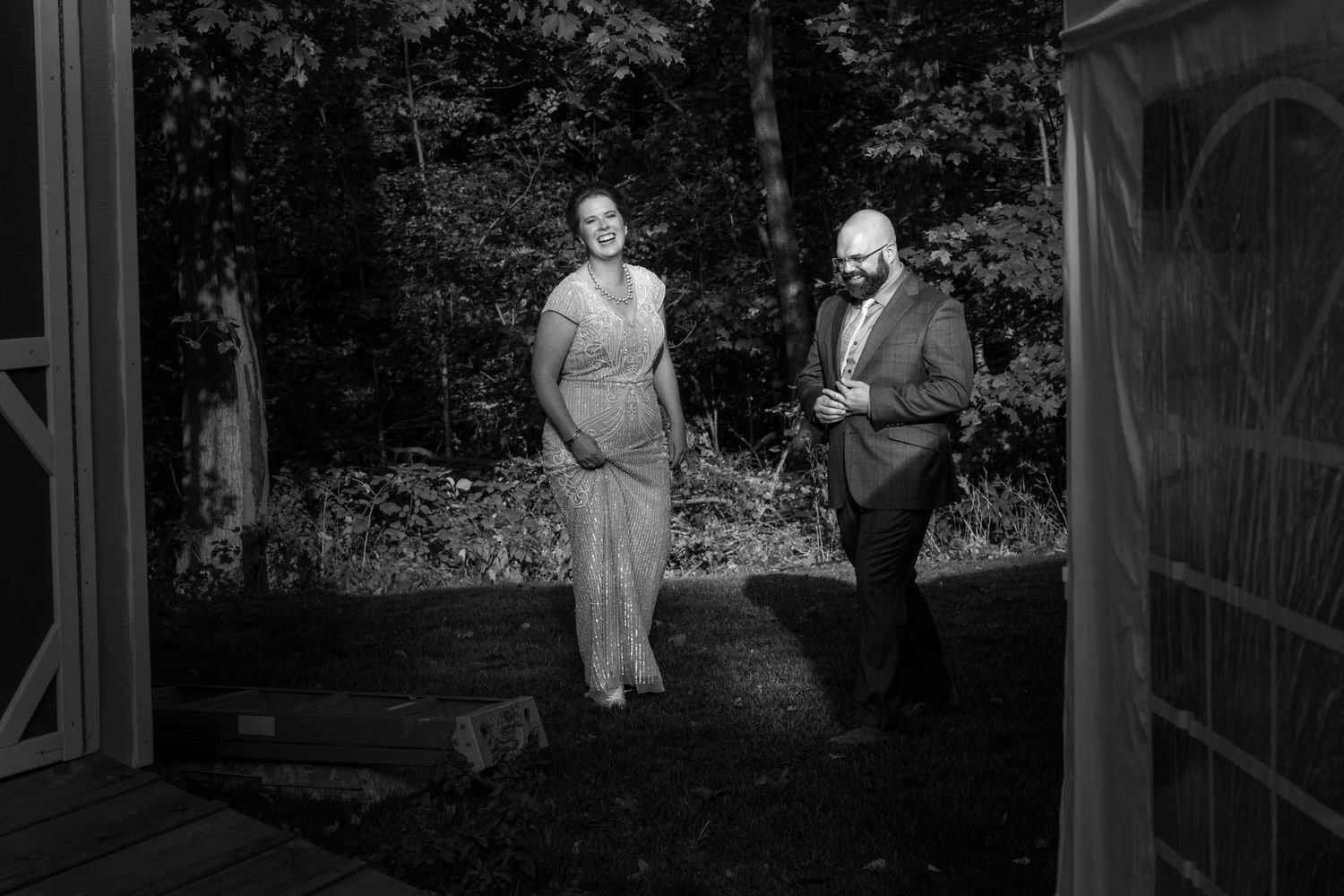 A unique and moody black and white photograph of a bride and groom standing the direct sunlight at their wedding.