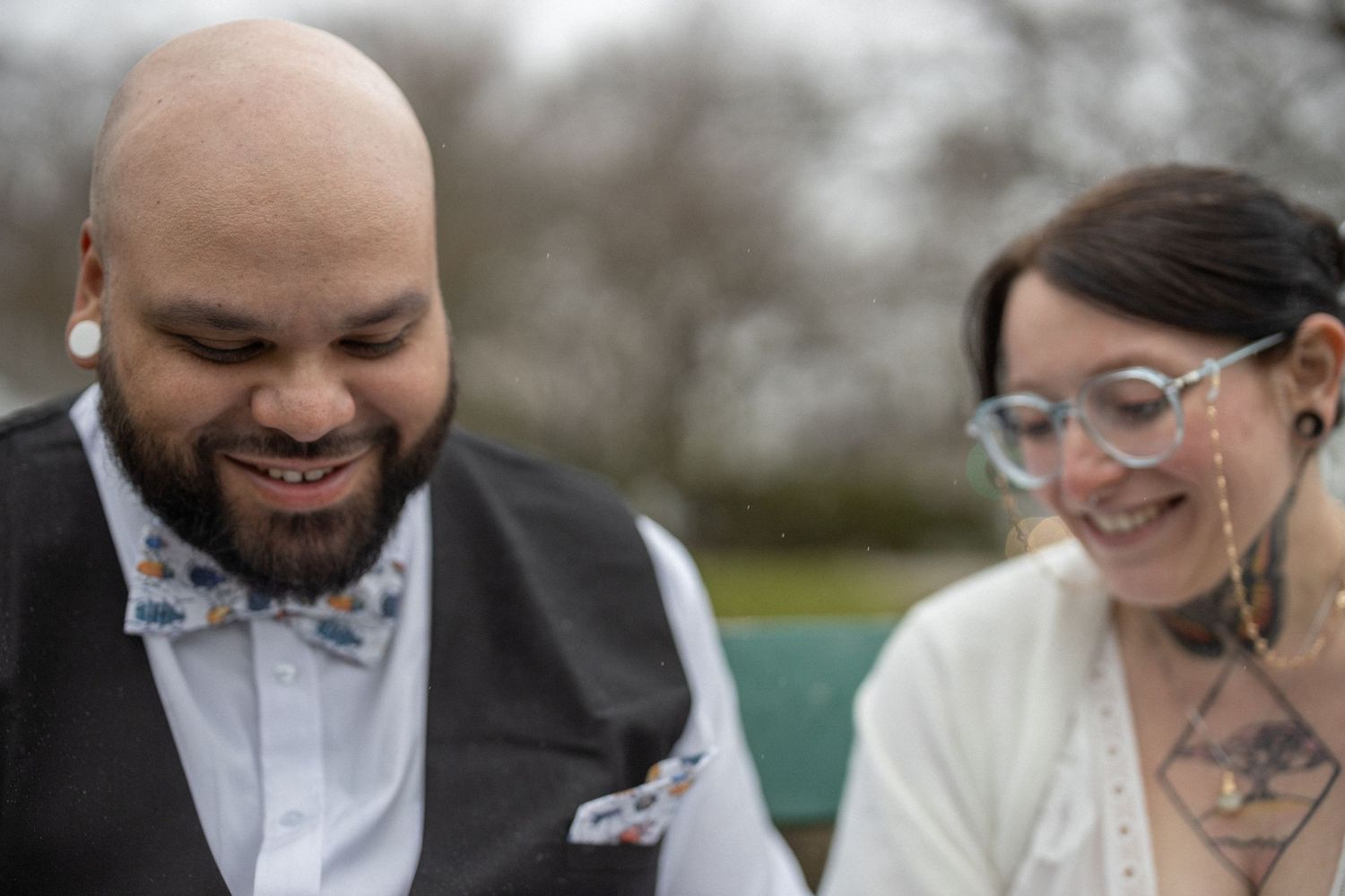 Wedding photographer holds up camera while smiling during outdoor photo session with wedding couple.