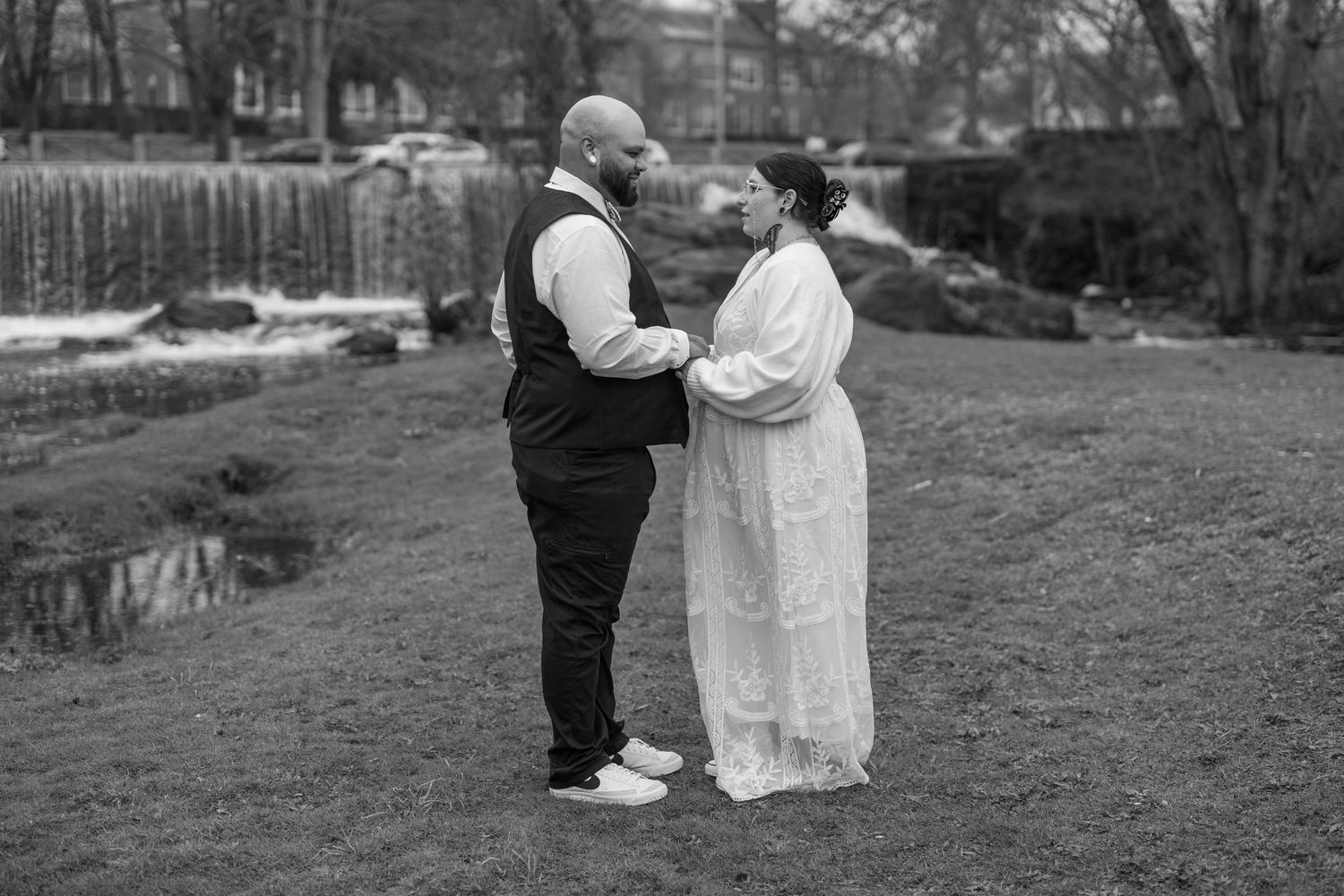 Black and white image of bride and groom looking into each others eyes while holding hands.