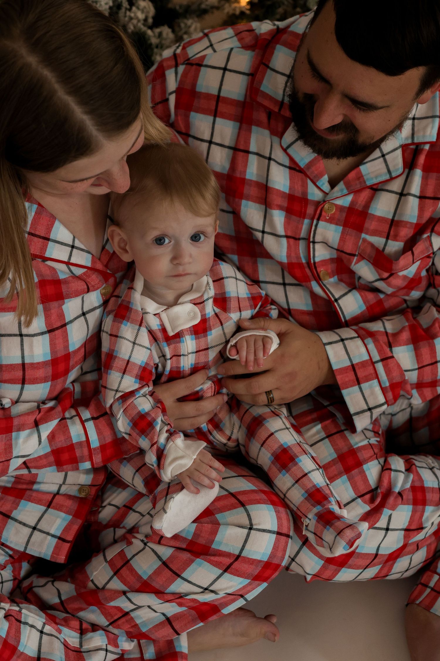 A family shares an intimate moment wearing matching plaid holiday pajamas.