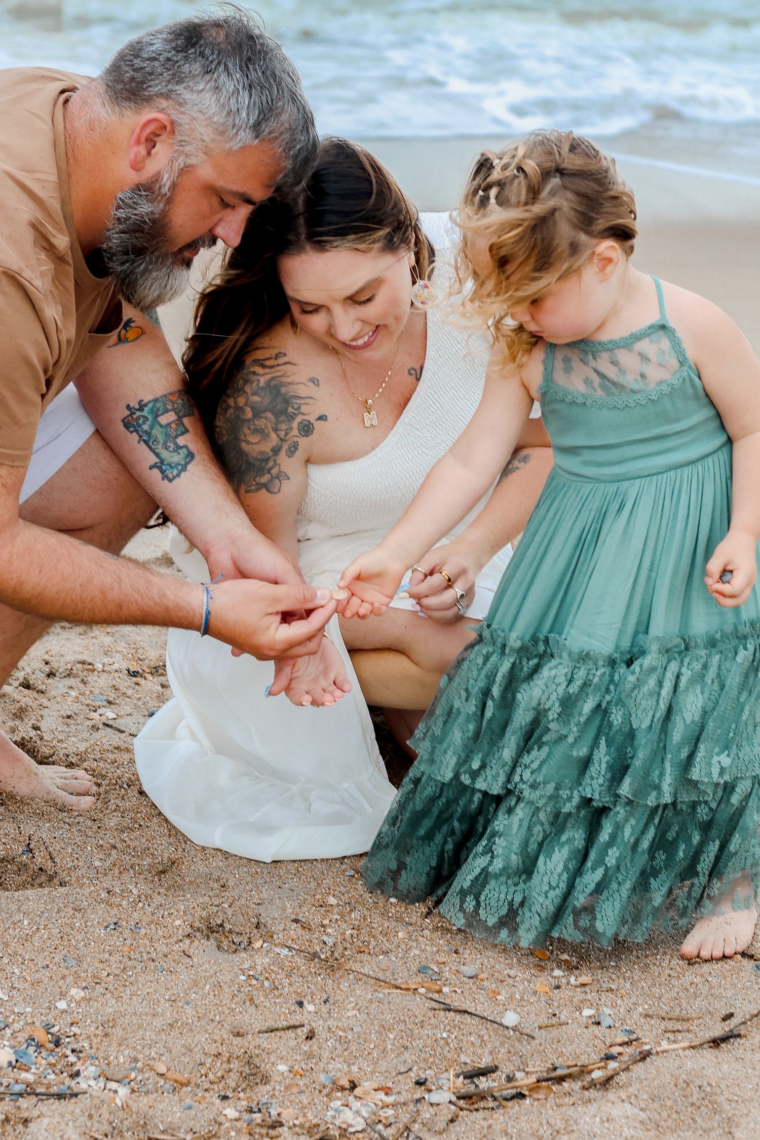 Family searching for seashells together on a sandy beach.