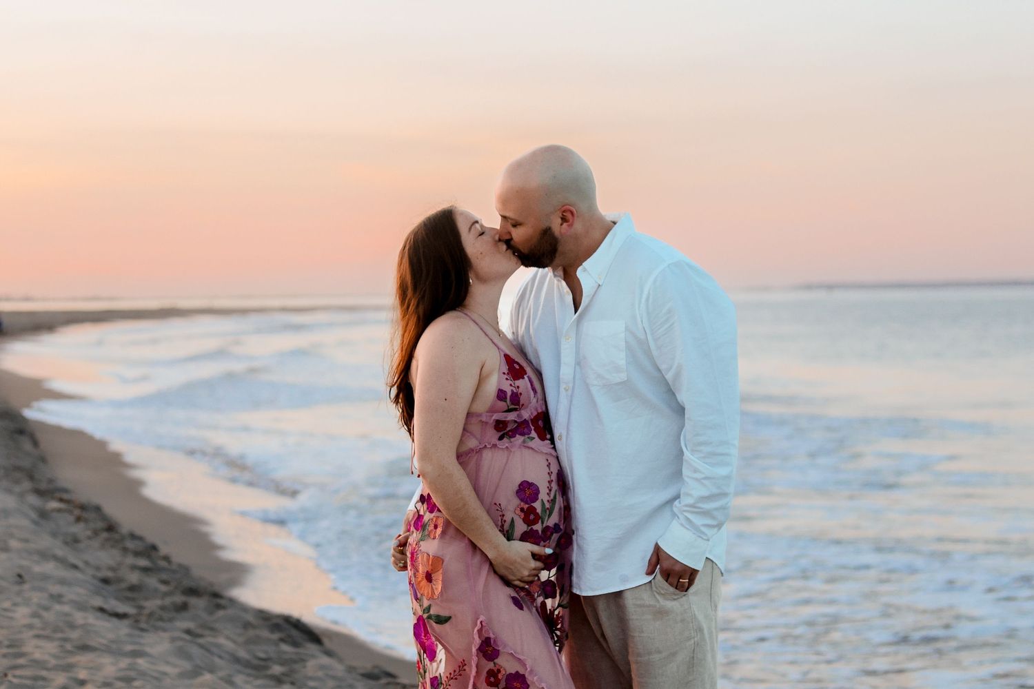 Intimate beach sunset moment with couple in white attire.