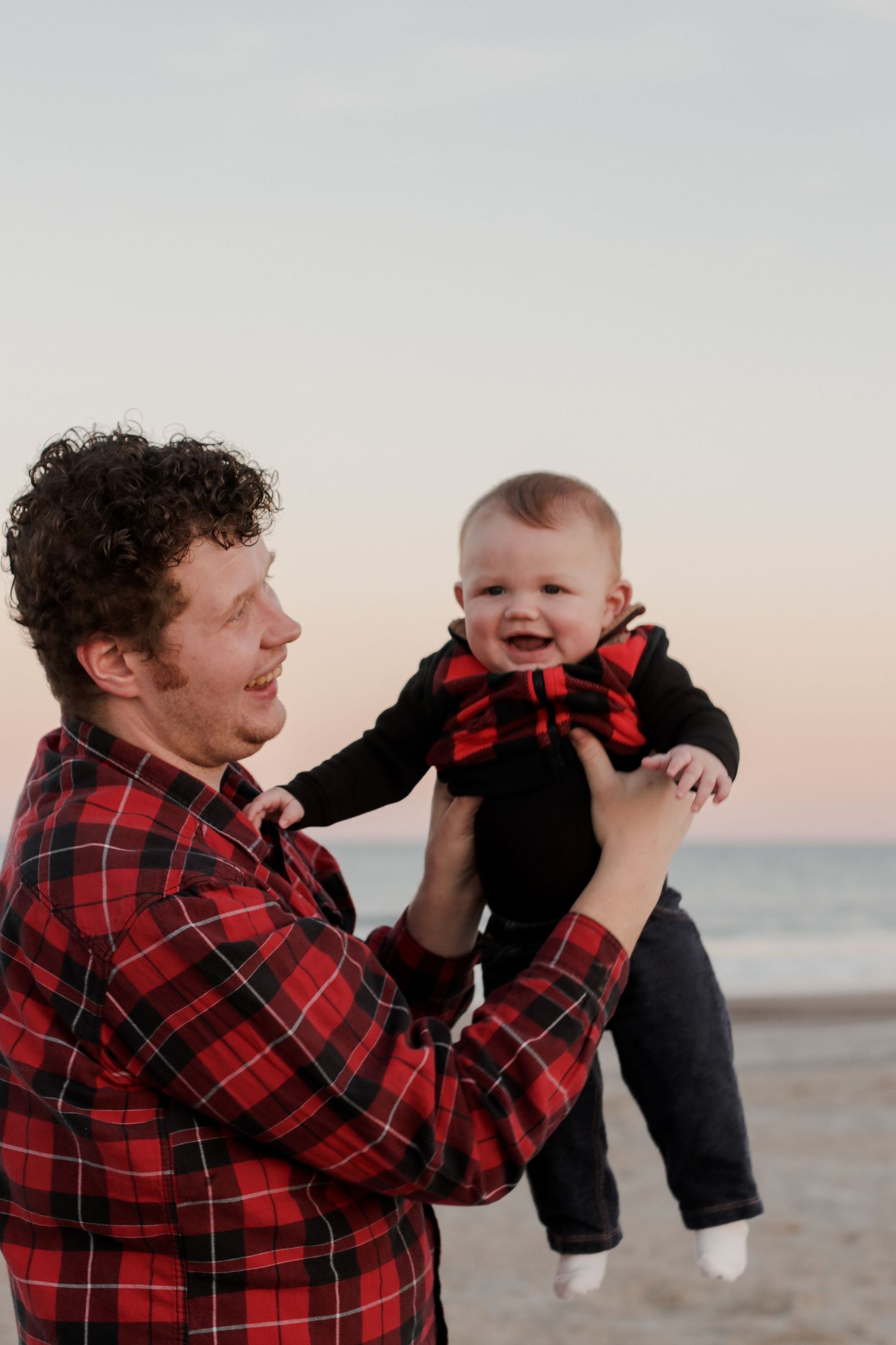 A joyful moment shared between parent and baby on the beach at sunset.