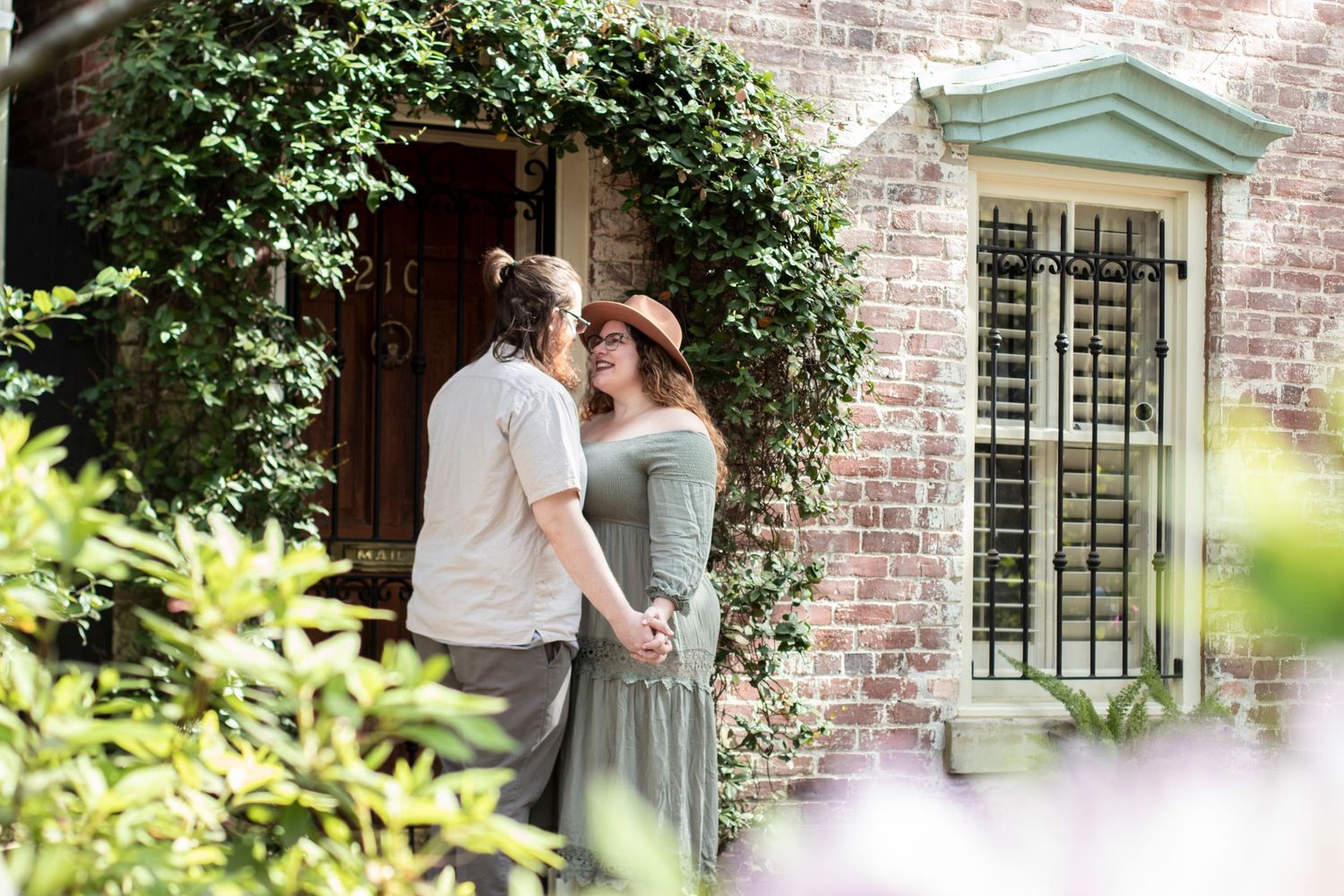 Brick building exterior with lush greenery and white garden flowers in bloom.