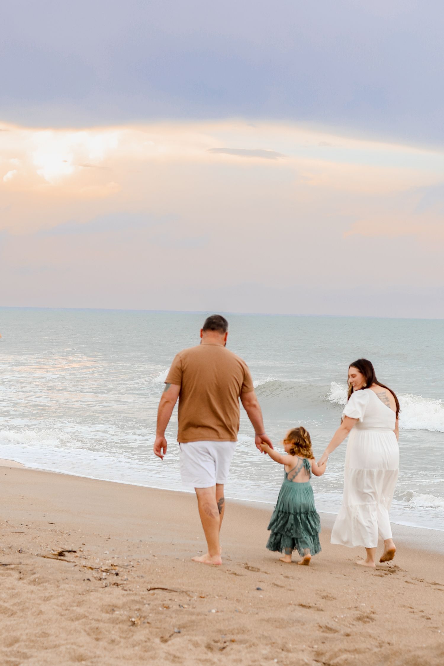 Family walking together along the shoreline during a sunset beach photo session.