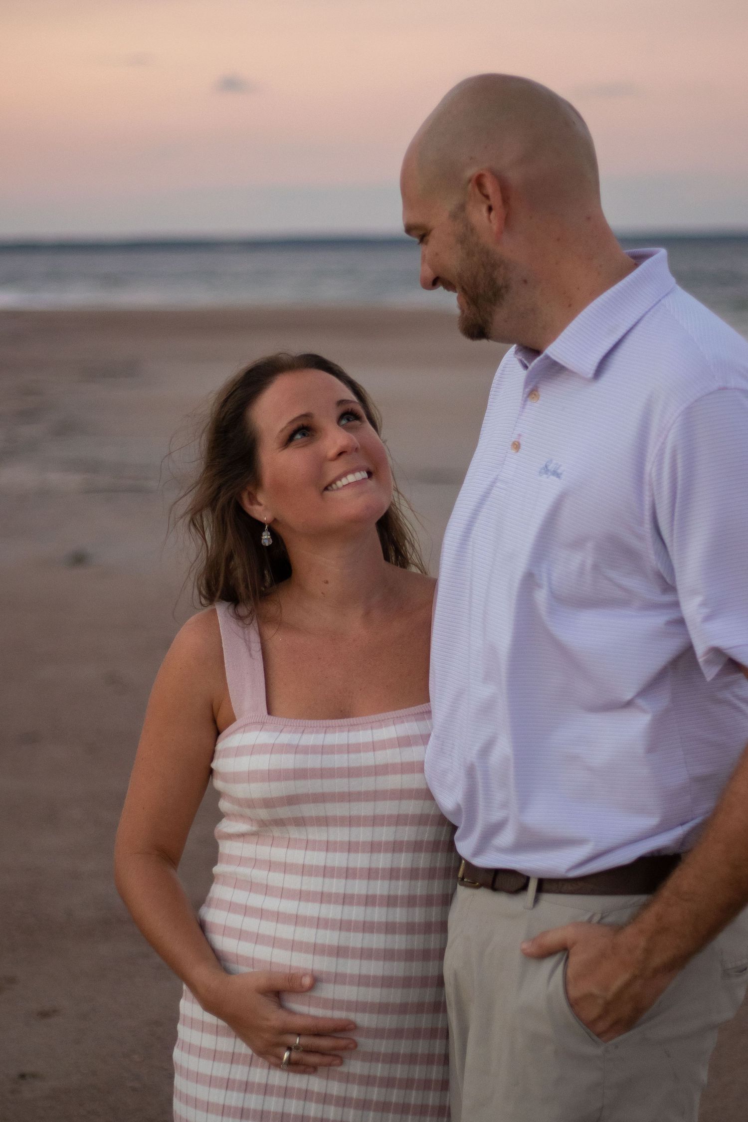 A couple shares an intimate moment on the beach during sunset.