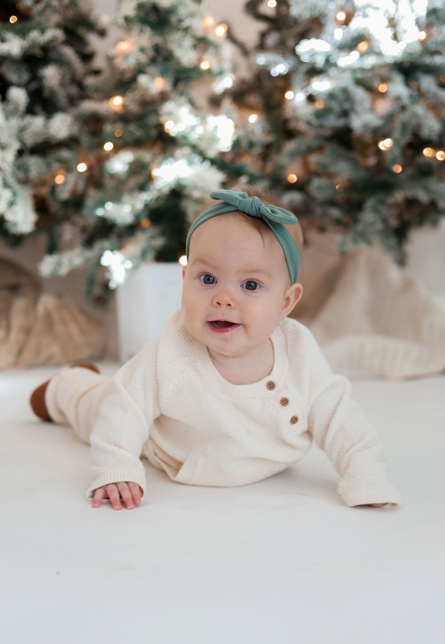 Sweet holiday portrait against flocked Christmas trees with twinkling lights.